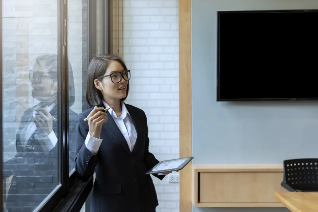 Businesswoman presenting beside a wall mounted display, showing a clean and professional TV installation in Singapore.