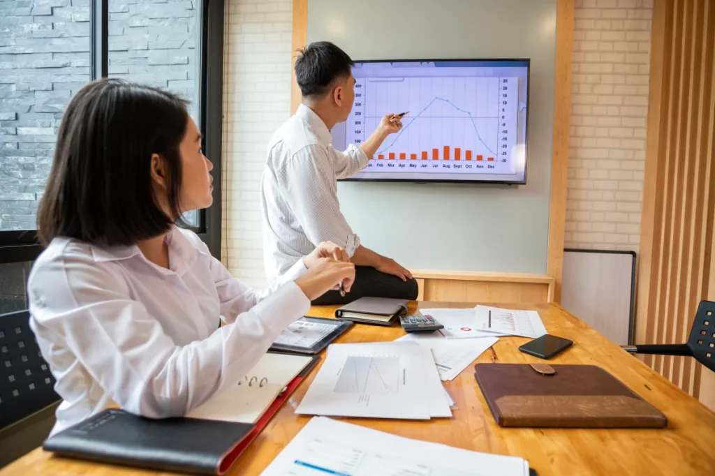 Business team reviewing data on a wall mounted display, demonstrating secure TV installation in Singapore.