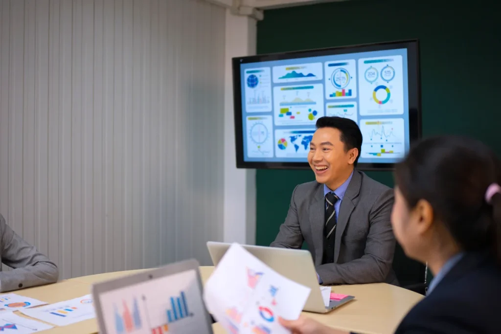 Team meeting with data displayed on a wall mounted screen, showing professional TV installation in Singapore for business use.