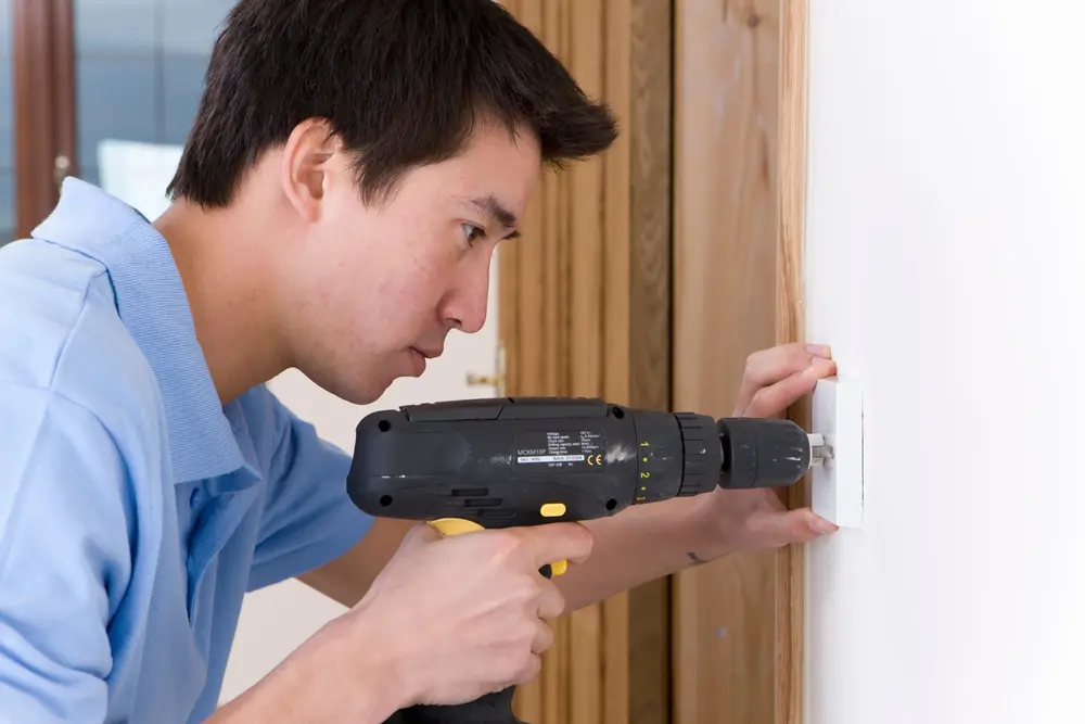 a man finding the best drilling spot for his TV bracket